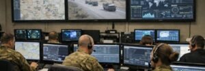 Military command operations centre showing real-time data integration across multiple screens representing JADC2 joint all-domain command and control